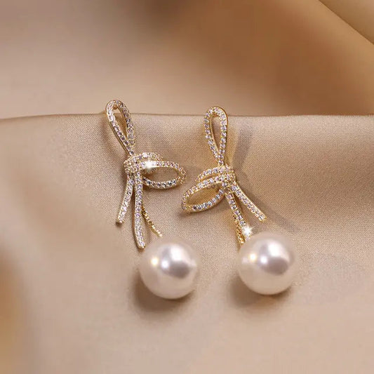 Pearl earrings with a glossy bow in gold Claire